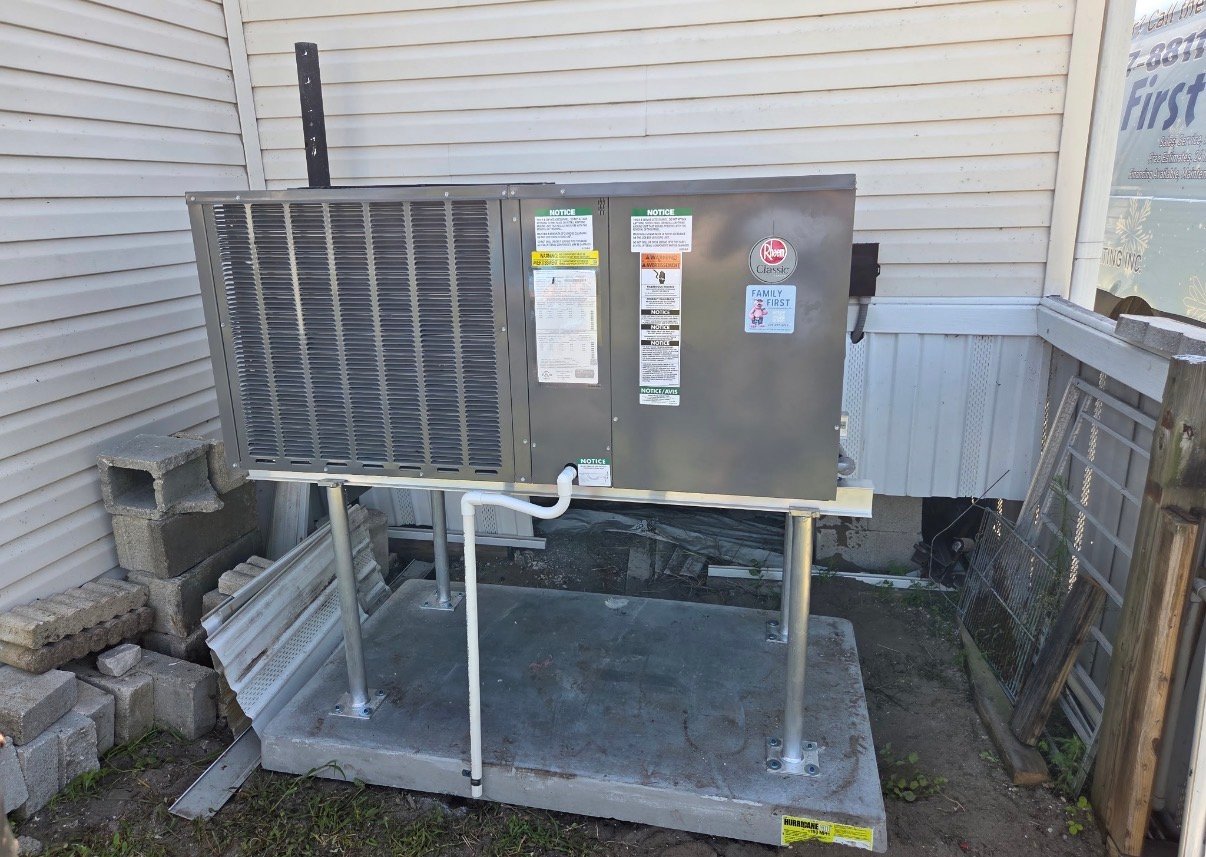 New Rheem packaged HVAC unit installed on a raised concrete pad beside a mobile home in Punta Gorda, FL