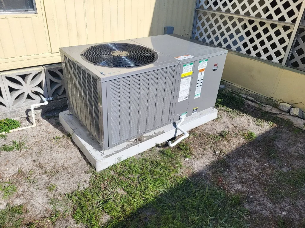 New Rheem packaged HVAC unit installed on a raised pad beside a mobile home in Punta Gorda, FL