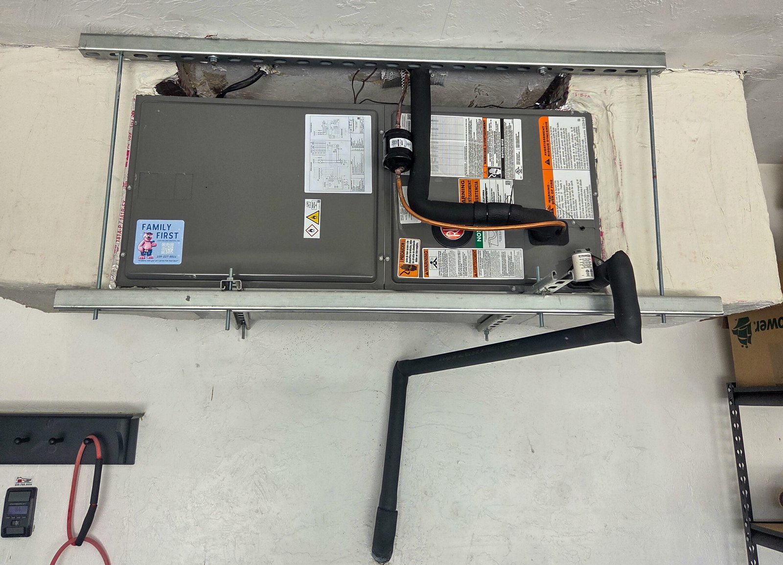 New Rheem air handler with Family First Cooling & Heating sticker installed horizontally in a garage ceiling